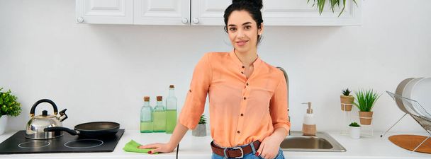 Een stijlvolle vrouw in casual kleding houdt vol vertrouwen een koekenpan in de keuken. - Foto, afbeelding