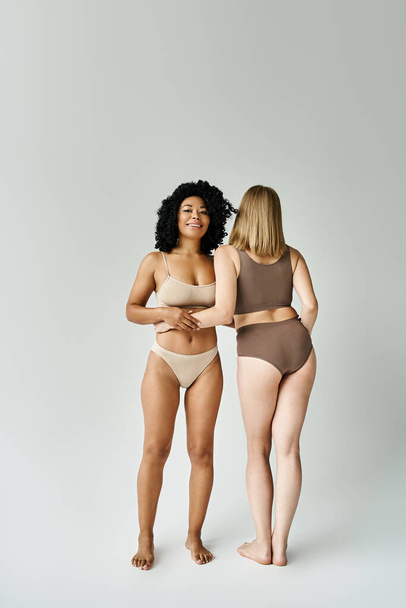Dvě krásné různé ženy v útulné pastelové spodní prádlo stojí vedle sebe. - Fotografie, Obrázek