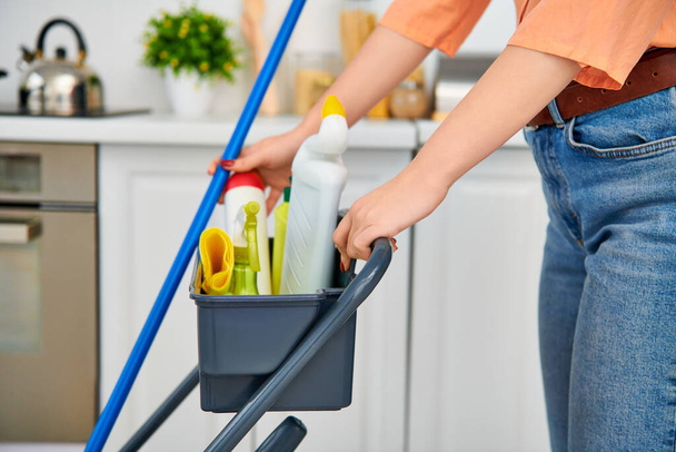 Una donna elegante in abbigliamento casual pulisce con grazia il pavimento con uno straccio nella sua casa. - Foto, immagini
