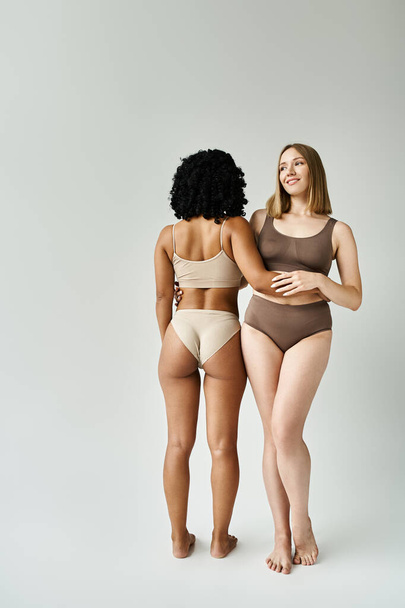 Two diverse women in cozy pastel bikinis standing side by side. - Photo, Image