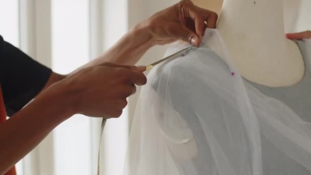 Plan recadré d'égouts méconnaissables faisant des mesures de robe de mariée travaillant ensemble en atelier - Séquence, vidéo