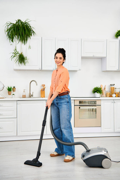 Eine stilvolle Frau in legerer Kleidung saugt anmutig den Boden ihres Hauses. - Foto, Bild