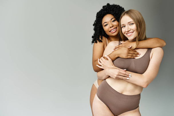 Deux belles femmes diversifiées en maillots de bain pastel s'embrassant chaleureusement. - Photo, image