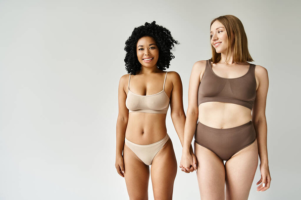 Deux belles femmes diversifiées dans des bikinis pastel confortables debout ensemble. - Photo, image