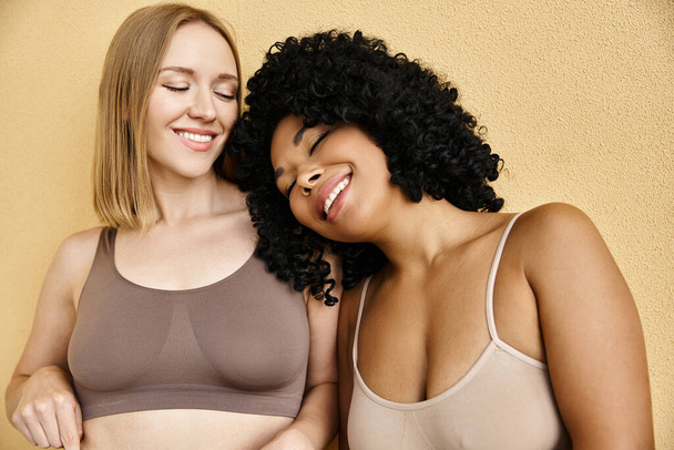 Deux belles femmes diversifiées se tiennent côte à côte dans des sous-vêtements pastel confortables. - Photo, image