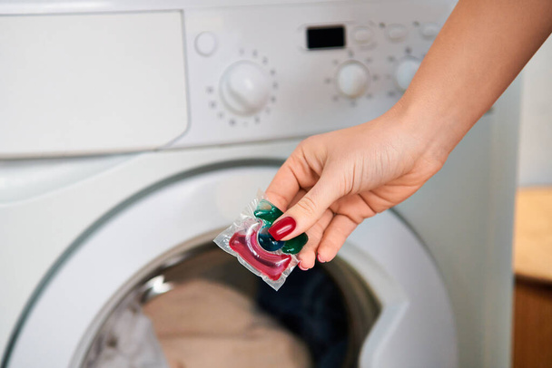 Eine stylische Frau hält eine Tüte Bonbons vor einer Waschmaschine. - Foto, Bild