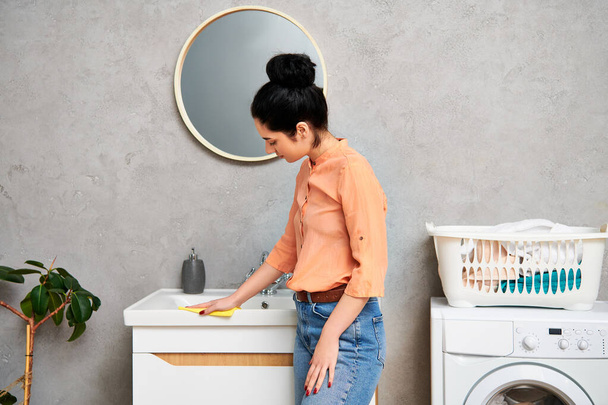 Stylowa kobieta w stroju casual stojąca przed pralką, gotowa do pracy w gospodarstwie domowym. - Zdjęcie, obraz
