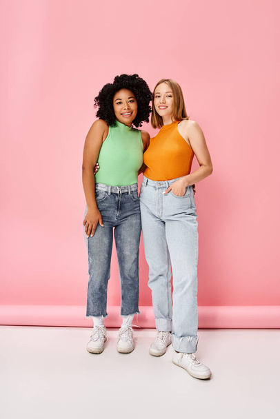Δύο διαφορετικές γυναίκες στέκονται η μία δίπλα στην άλλη μπροστά σε ένα ροζ τοίχο.. - Φωτογραφία, εικόνα