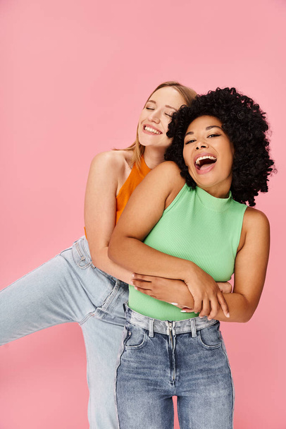 Dos mujeres jóvenes se abrazan frente a un fondo rosa. - Foto, imagen