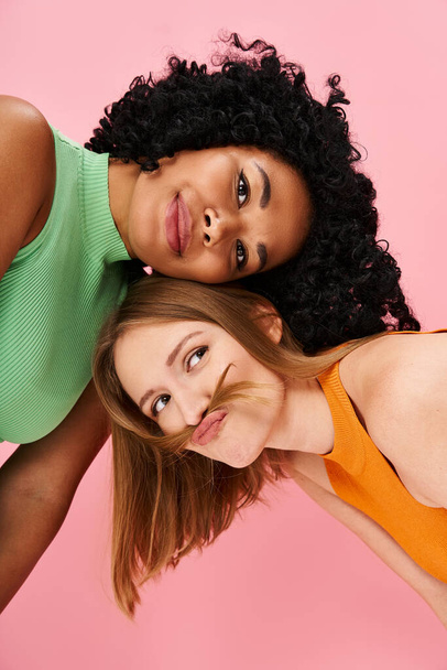 Two stylish women striking a pose in front of a pink background. - Photo, Image