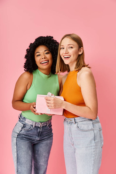 Две различные женщины элегантно стоят вместе на мягком розовом фоне. - Фото, изображение