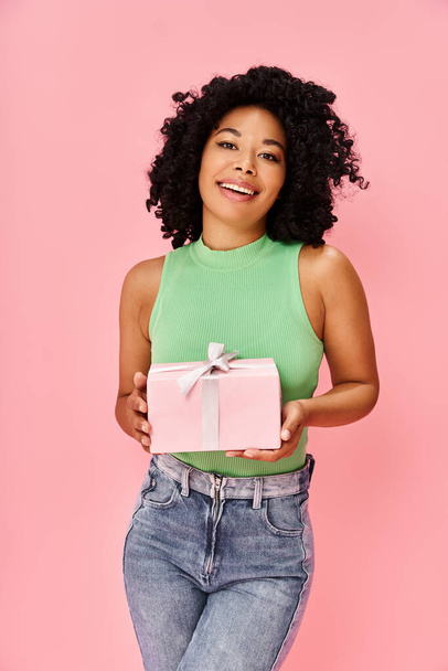 Egy zöld inges nő rózsaszín ajándékdobozt tart a kezében.. - Fotó, kép