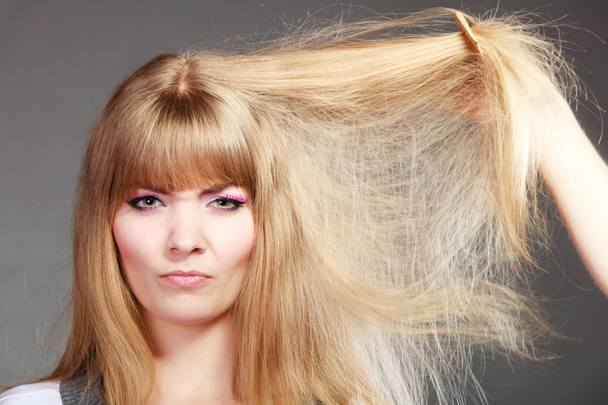 Blonde woman combing dry hair. - Foto, Bild