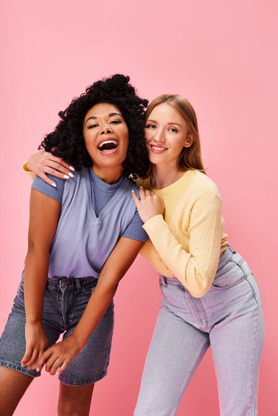 Δύο διαφορετικές γυναίκες στέκεται με αυτοπεποίθηση σε άνετο casual ενδυμασία σε ένα ροζ φόντο. - Φωτογραφία, εικόνα
