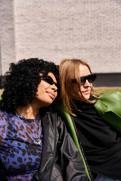 Zwei unterschiedliche Frauen, lässig gekleidet, eng beieinander sitzend mit einem warmen und freundlichen Auftreten. - Foto, Bild