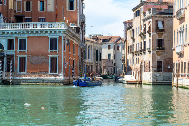 ヴェネツィア,ヴェネト - イタリア 06-10-2021: 歴史的な建物に囲まれた静かなヴェネツィア運河の貨物船 - 写真・画像