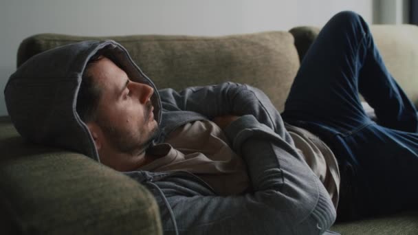 Thoughtful man at home on sofa - Footage, Video