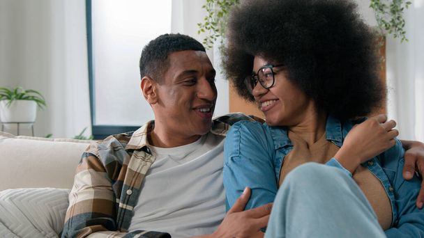Africký americký šťastný rodinný pár v lásce náklonnost bonding mluvení komunikovat mluvit konverzace příležitostné mluvení diskutovat o sdílení zpráv přítel muž a přítelkyně žena doma gauč - Fotografie, Obrázek
