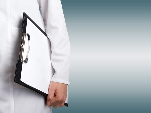Female doctor's hand holding medical clipboard with blank sheet of paper on blurred background. Concept of Healthcare And Medicine. Copy space. - Foto, Imagem