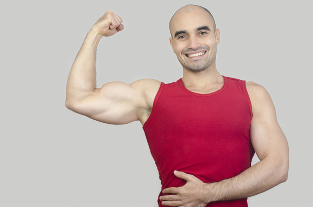 Happy bodybuilder showing his biceps. - Foto, afbeelding