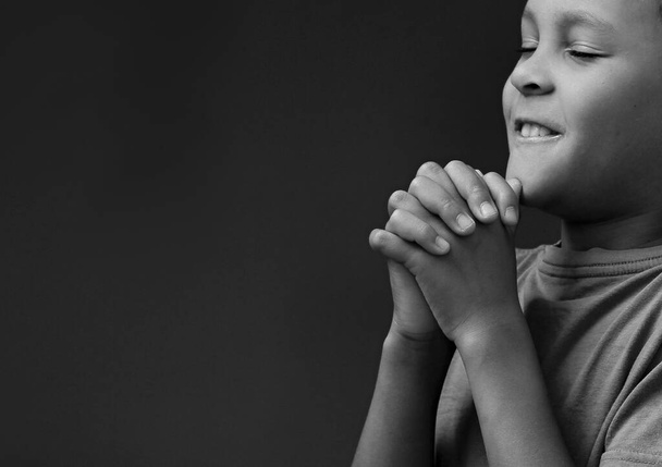 Child boy praying to God with hands together on white background  - Photo, Image