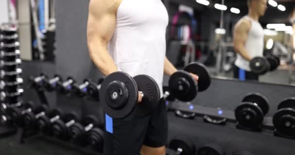 Atleta masculino levantando halteres e músculos do braço de treinamento no ginásio filme 4k câmera lenta. Treinamento esportivo e conceito de estilo de vida saudável - Filmagem, Vídeo