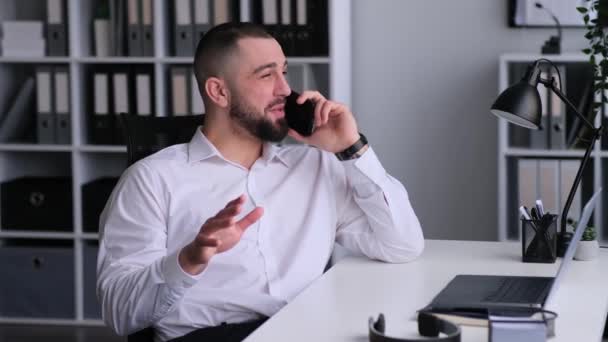 Usmívající se kavkazský zaměstnanec konzultující klienta a smějící se během telefonátu, pracující v kanceláři. Online konverzace, telekomunikační koncept. - Záběry, video
