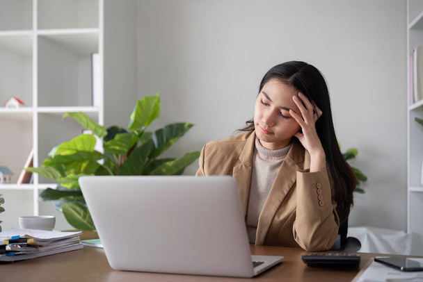 不幸なアジアのビジネス女性は,落ち着いた緑の植物で装飾されたホームオフィスで働いている間,失敗したビジネス上のストレスを示しています.. - 写真・画像