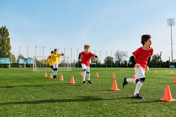Een groep jonge jongens spelen enthousiast voetbal op een weelderig groen veld. Ze rennen, schoppen en passeren de bal terwijl ze teamwork en sportiviteit tonen.. - Foto, afbeelding