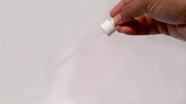 Trage beweging close-up video van een aziatische man met behulp van een druppelaar druipend water uit druppelaar - Video