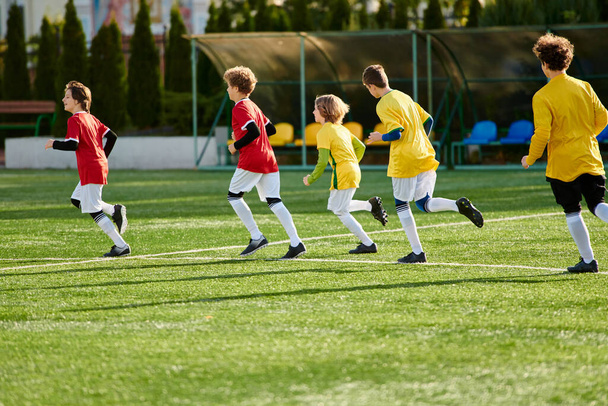 Μια ομάδα από δραστήρια νεαρά αγόρια βυθίζονται σε ένα παιχνίδι ποδοσφαίρου, dribbling και πασάροντας την μπάλα με ενθουσιασμό. Τρέχουν, κλοτσάνε και φωνάζουν με χαρά καθώς ανταγωνίζονται στο γήπεδο.. - Φωτογραφία, εικόνα