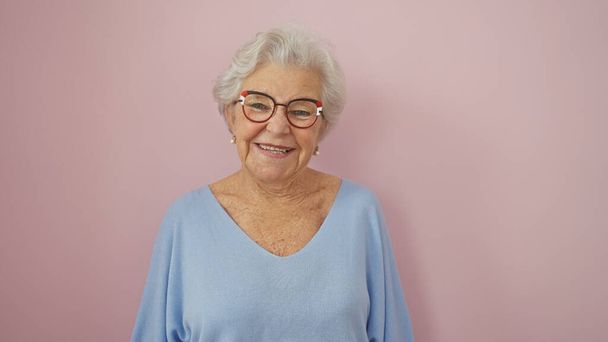 Une femme âgée joyeuse portant des lunettes souriant sur un fond rose, dépeignant positivité et vieillissement gracieusement. - Photo, image