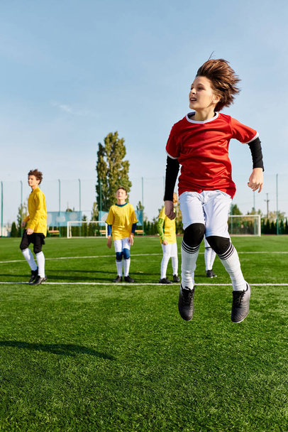 Een groep jonge kinderen, vol energie en opwinding, zijn betrokken bij een vriendschappelijk voetbalspel op een uitgestrekt groen veld. Ze rennen, schoppen, passen en juichen elkaar toe onder de warme zon. - Foto, afbeelding