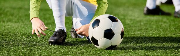 Un niño pequeño juega alegremente con una pelota de fútbol, pateándola con emoción y entusiasmo. - Foto, imagen