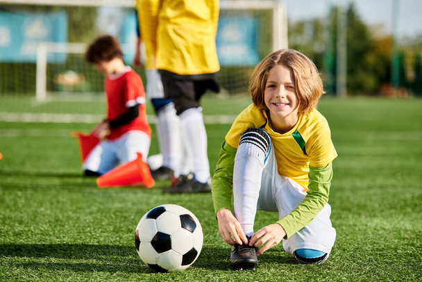 Ένα νεαρό κορίτσι με ένα φωτεινό χαμόγελο παίζει με μια μπάλα ποδοσφαίρου, κλοτσιές και ντρίμπλα με ενθουσιασμό σε ένα χορταριασμένο πεδίο σε μια ηλιόλουστη μέρα. - Φωτογραφία, εικόνα