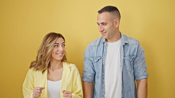 Hombre y mujer pareja sonriendo confiados de pie juntos sobre fondo amarillo aislado - Foto, imagen
