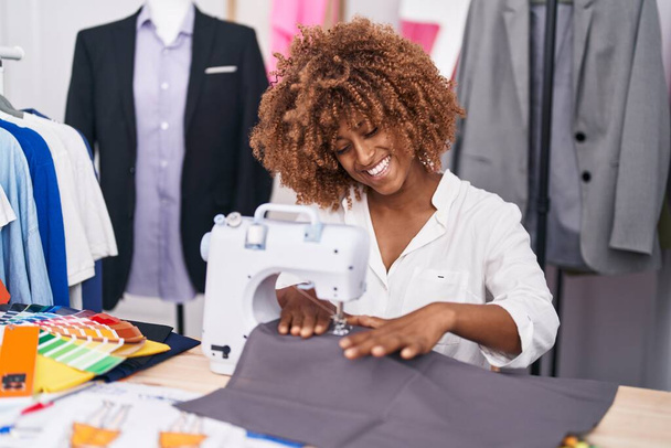 Afrikkalainen amerikkalainen nainen räätälöidä hymyilevä luottavainen käyttäen ompelukone atelier - Valokuva, kuva