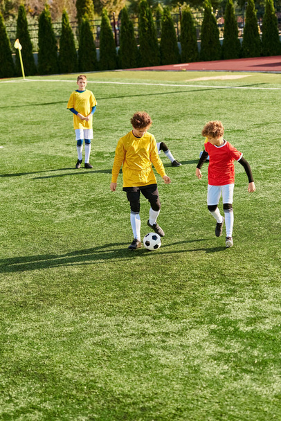 Группа энергичных маленьких детей, занимающихся живой игрой в футбол, с радостью и энтузиазмом пинает мяч взад и вперед по солнечному полю. - Фото, изображение
