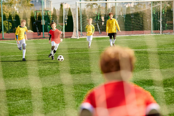 Grupa żywych małych dzieci entuzjastycznie grających w piłkę nożną, biegających, kopiących piłkę i dopingujących się nawzajem w żywy i porywający sposób. - Zdjęcie, obraz