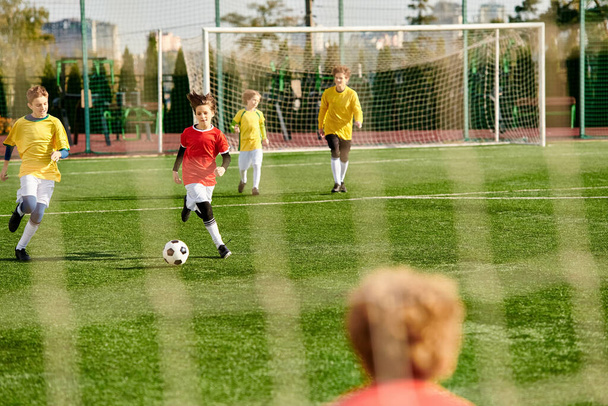 Группа молодых людей, участвующих в энергичной игре в футбол на зеленом поле, гоняющихся за мячом, показывающих командную работу, мастерство и решимость, когда они соревнуются в напряженном матче. - Фото, изображение
