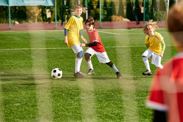 Жива група маленьких дітей грає в футбол на зеленому полі. Вони бігають, штовхають і проходять м'яч, коли змагаються в товариському матчі, наповненому сміхом і хвилюванням. - Фото, зображення