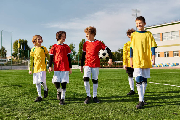 Un grupo de niños pequeños de pie orgullosamente en la parte superior de un campo de fútbol, celebrando su victoria con sonrisas y choca los cinco. - Foto, Imagen
