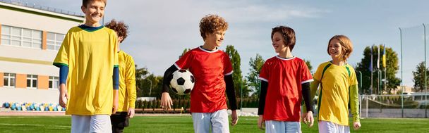 Eine Gruppe junger Männer in Fußballkleidung steht Schulter an Schulter auf einem Fußballplatz. Sie wirken fokussiert und bereit zu spielen, mit dem grünen Gras und den Torpfosten im Hintergrund. - Foto, Bild