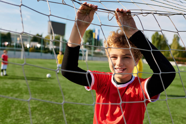 Een jonge jongen staat vol vertrouwen voor een voetbaldoelpunt, gericht op het scoren van een doelpunt. Zijn houding straalt vastberadenheid en passie voor het spel, als hij zich voorbereidt op een schot te nemen. - Foto, afbeelding