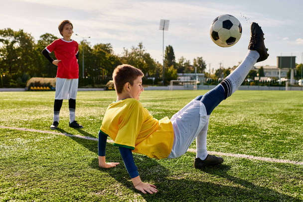 Uduchowiony młody chłopak energicznie kopie piłkę nożną przez bujne zielone pole, pokazując swój talent i miłość do sportu. - Zdjęcie, obraz
