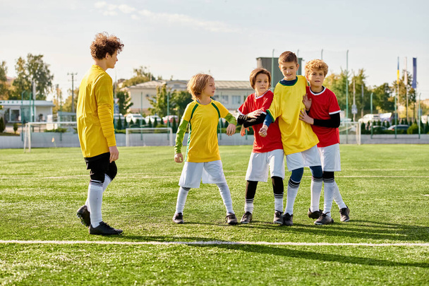 Een levendige groep jonge kinderen triomfantelijk staan op het weelderige groene voetbalveld, hun gezichten stralen van vreugde en prestaties. De ondergaande zon werpt een warme gloed over de scène als ze hun teamwork en overwinning vieren. - Foto, afbeelding