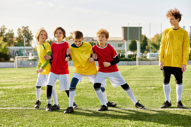 Fiatal egyének élénk csoportja áll büszkén a focipálya tetején, energiát és lelkesedést árasztva. Egyesülnek a játék iránti szeretetükben, a bajtársiasságuk nyilvánvaló mosolyukban és pózaikban.. - Fotó, kép