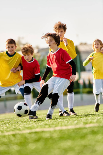 Un grupo de enérgicos niños pequeños jugando con entusiasmo un juego de fútbol en un campo de hierba. Están pateando una bola colorida, corriendo, riéndose y animándose mutuamente.. - Foto, imagen