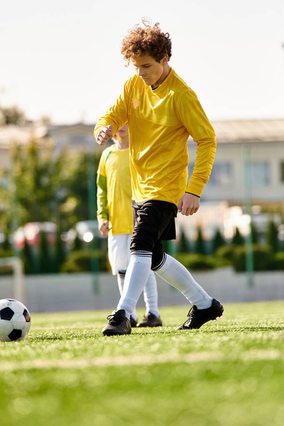 Dos jóvenes pateando enérgicamente una pelota de fútbol en un campo soleado, mostrando sus habilidades y trabajo en equipo. - Foto, imagen