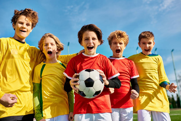 Різноманітна група молодих людей стоїть разом, формуючи коло, кожна людина тримає футбольний м'яч. Вони усміхаються і здаються захопленими і об'єднаними, демонструючи свою любов до спорту. - Фото, зображення